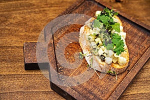 bruschetta with cheese and greens on a wooden cutting board for photos