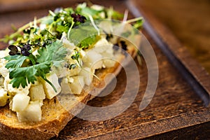 bruschetta with cheese and greens on a wooden cutting board for photos