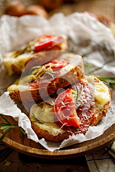 Bruschetta with cheese, salami and tomato sprinkled with rosemary