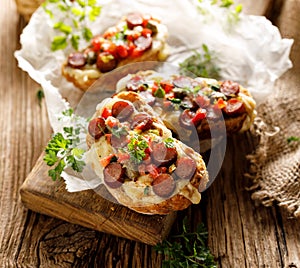 Bruschetta with cheese and sausage sprinkled with herbs