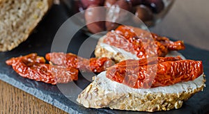 Bruschetta with dried tomatoes and soft cheese with boil of olives. Traditional Italian cuisine sandwich. Antipasti
