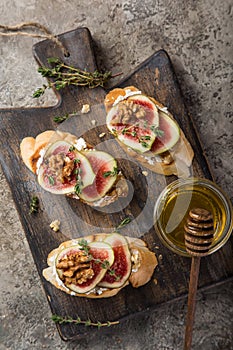 Bruschetta with goat cheese, figs, nuts and honey on cutting board