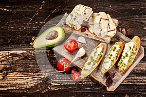 Bruschetta with grilled cheese halumi, avocado and cherry on a wooden background. Preparation of cheese Halumi. Cheese Halumi with