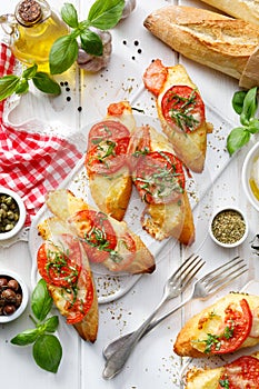 Bruschetta, grilled slices of baguette with mozzarella cheese, tomatoes, garlic and aromatic basil on a white wooden table