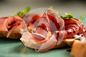 Bruschetta with jamon and soy sauce, pork ham served with white bread on a plate