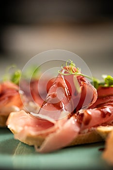 Bruschetta with jamon and soy sauce, pork ham served with white bread on a plate