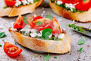 Bruschetta with pesto sauce, feta cheese, tomatoes and basil