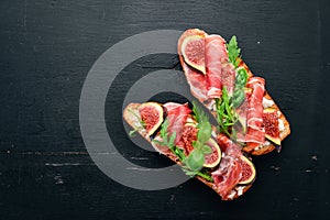 Bruschetta with prosciutto, fresh figs and cheese. On the old background. Healthy food. Free space for text.