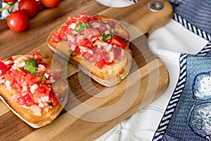 Bruschetta with rustic bread, cherry tomatoes, parsley and onion with olive oil on the wooden board.