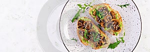 Bruschetta. Sandwich with avocado, fried mushrooms, sesame on a white table. Vegetarian food. Vegan menu. Top view, overhead,