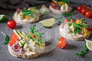 Bruschetta with tomato, avocado, herbs and arugula. Rustic background. Top view