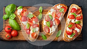 Bruschetta with tomatoes, mozzarella cheese and basil on a cutting board. Traditional italian appetizer or snack, antipasto. Top v
