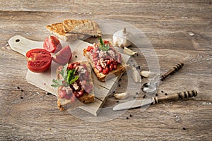 Bruschetta with tomatoes and tuna on wood background