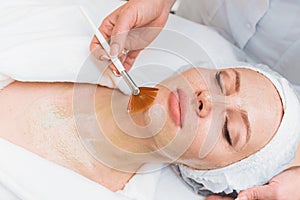 Brush applies an enzyme mask to a woman`s face