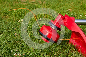 Brush cutter with the grass,a new red mower lies on the grass, work in the garden, mow the grass