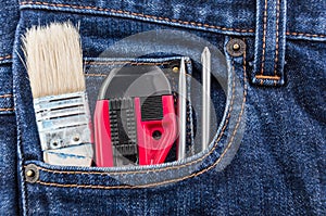 Brush, cutter and screwdriver in blue jean pocket