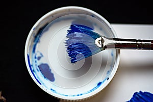 Brush dipped in blue gouache lies on the lid