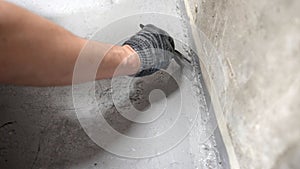 Brush with gray primer. A man paints the concrete floor in his bathroom with a gray brush. Waterproofing the floor in