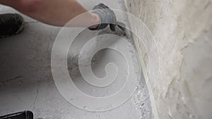 Brush with gray primer. A man paints the concrete floor in his bathroom with a gray brush. Waterproofing the floor in