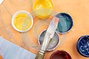 brush and jars of multi-colored paints with covers. Background for an article about drawing