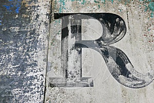 Brush lettered capital R on grungy metal surface