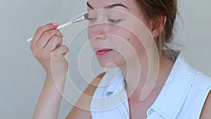 Brush make up girls hand in white room doing makeup shadows