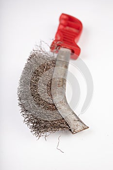 A brush with metal prongs on a white table. Tools for the slusier to clean the material