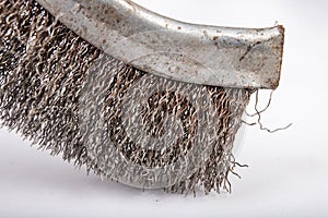 A brush with metal prongs on a white table. Tools for the slusier to clean the material