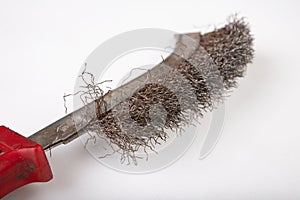 A brush with metal prongs on a white table. Tools for the slusier to clean the material