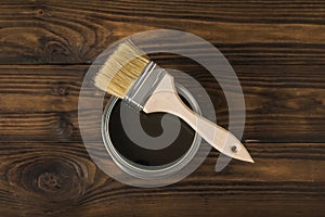 Brush on an open jar with a tinting composition on a wooden background