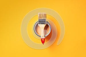 Brush and open paint can with on trendy yellow background. Top view, copy space. Appartment renovation, repair, building