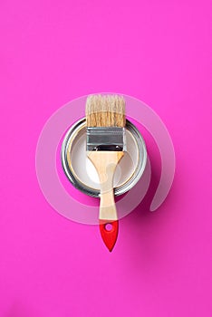 Brush and open paint can with on trendy yellow background. Top view, copy space. Appartment renovation, repair, building