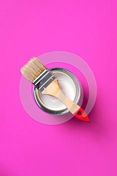 Brush and open paint can with on trendy yellow background. Top view, copy space. Appartment renovation, repair, building