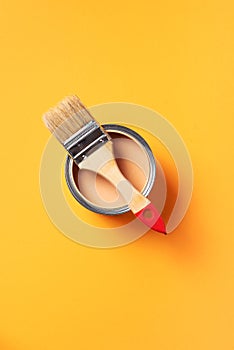 Brush and open paint can with on trendy yellow background. Top view, copy space. Appartment renovation, repair, building