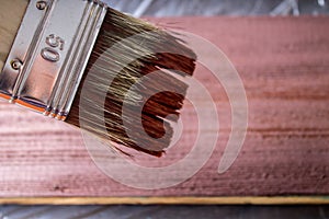 Brush with paint in hand. A man paints blue boards in a brown paint brush.