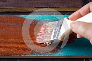 Brush with paint in hand. A man paints blue boards in a brown paint brush.