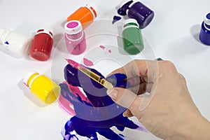 Brush with paints for painting, in a female hand.