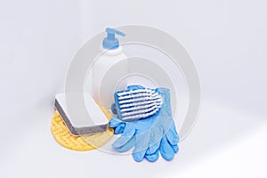 Brush, washcloth and rubber gloves in white bath