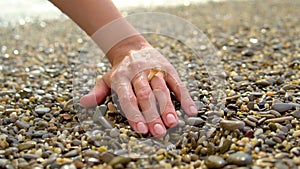 Brush your hand on it a ring of shell running a wave from the sea around the pebble on the beach seaside, slowmo