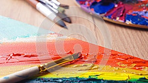 Brushes and artist`s palettes with colorful mixed paints on wooden table, closeup