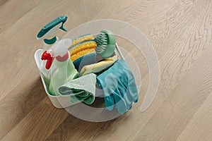 Brushes, bottles with cleaning liquids, sponges, and rubber gloves. Cleaning supplies on wooden floor