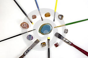 Brushes and colored stones against white background