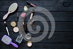 Brushes and combs, perfumes and various cosmetics lie on a black wooden board, cosmetics as a background, beauty