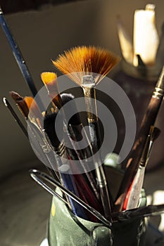brushes of different size and thickness inside a ceramic container on a table