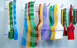 Brushes hang on shelf. Color coded hygiene glazing brushes and detail brushes for food processing and manufacturing. Cleaning tool