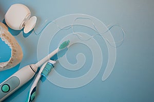 Brushes, model of the jaw and dental floss on a blue background