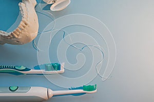 Brushes, model of the jaw and dental floss on a blue background