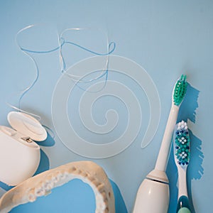 Brushes, model of the jaw and dental floss on a blue background