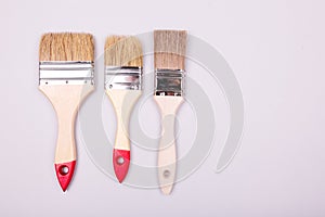 Brushes and an open can with red on plain gray background