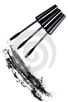 Brushes wands and smudged mascara on white background